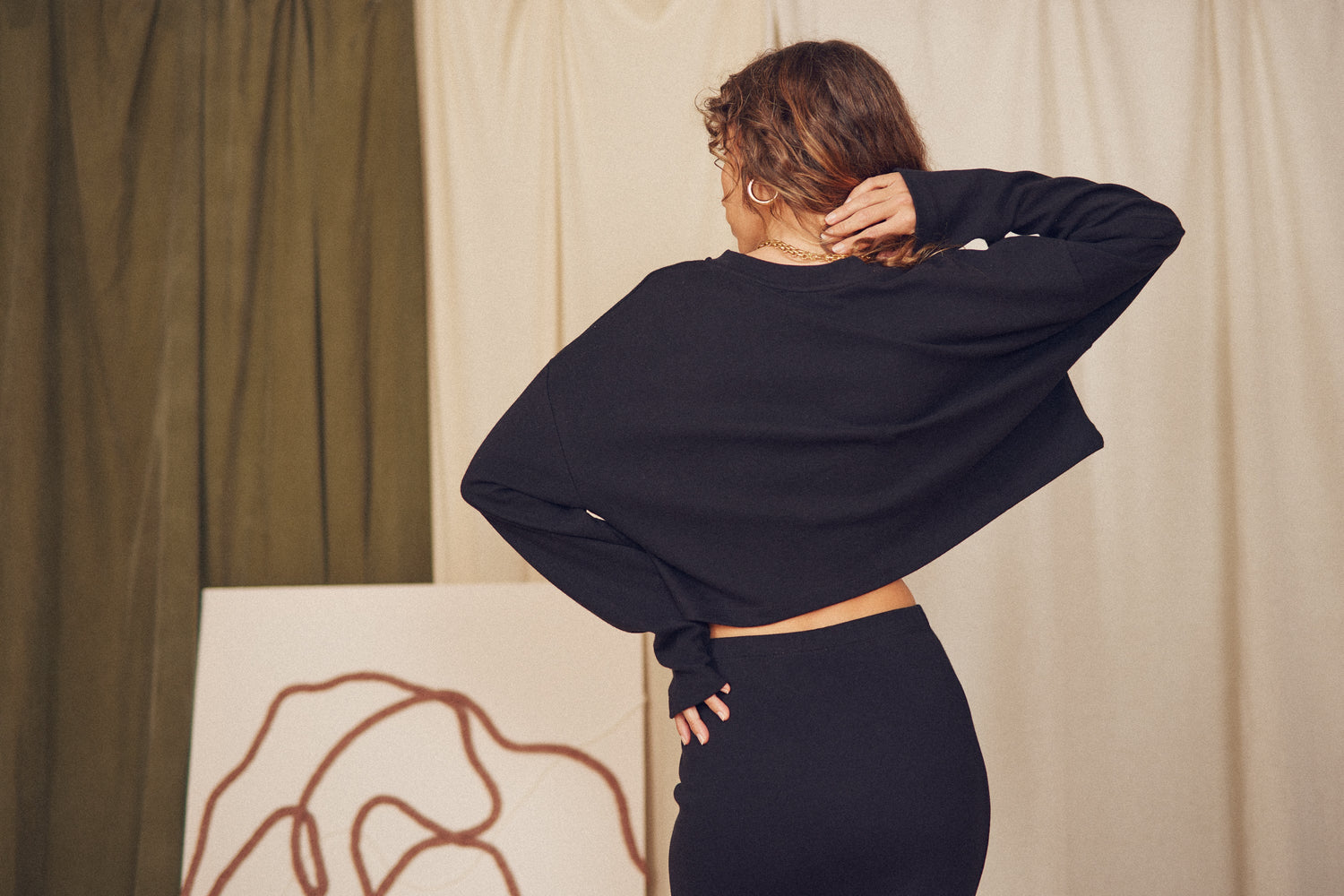 Stylish woman wearing a black cropped top and skirt, highlighting tops & bodysuits collection.