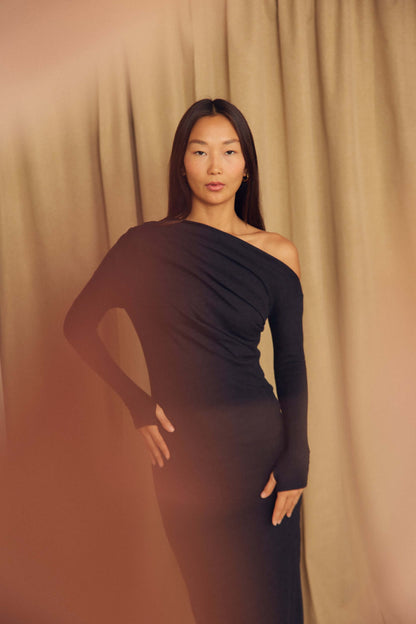 Black Wool Drape Midi Dress modeled by a woman with draped neckline against a soft background.