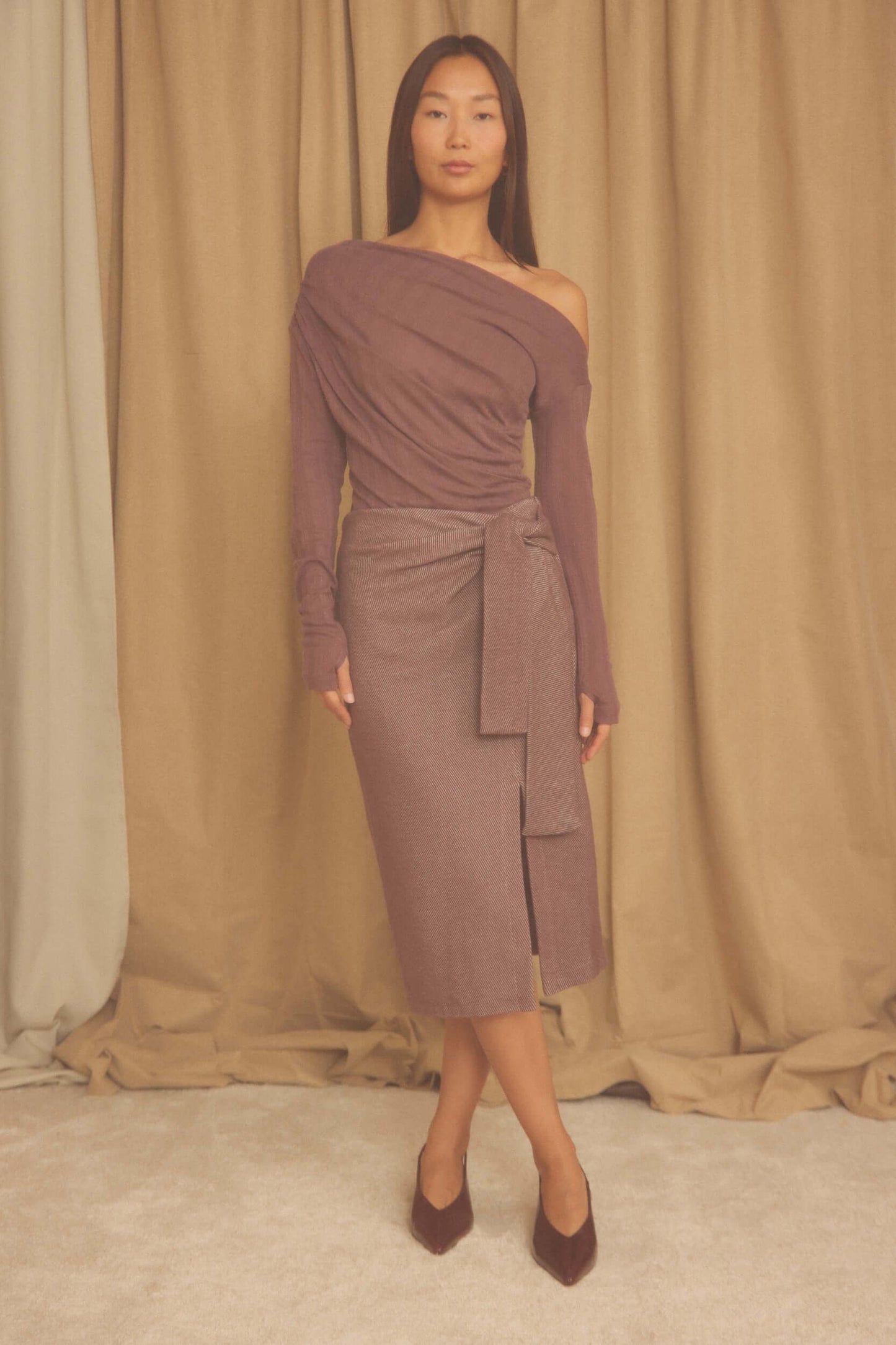 Model wearing Cocoa Lyocell Ribbed Drape Bodysuit in rich cocoa brown, showcasing elegant draped neckline and streamlined fit.