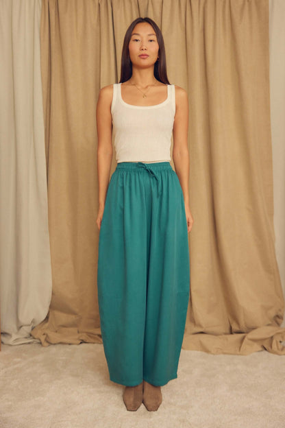 Model wearing an Ecru Lyocell Ribbed Tank Top paired with teal wide-leg pants, showcasing a soft and stylish outfit.