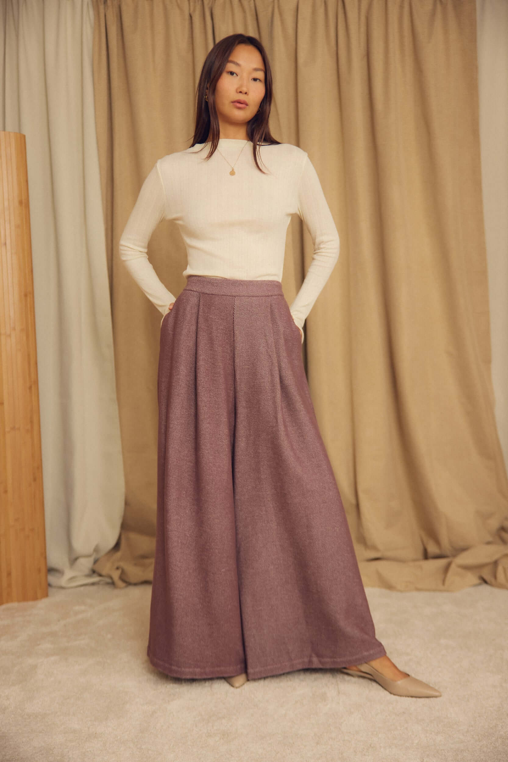 Model wearing Cocoa Organic Cotton Wide Trousers with a fitted top, showcasing the oversized silhouette in a stylish interior.