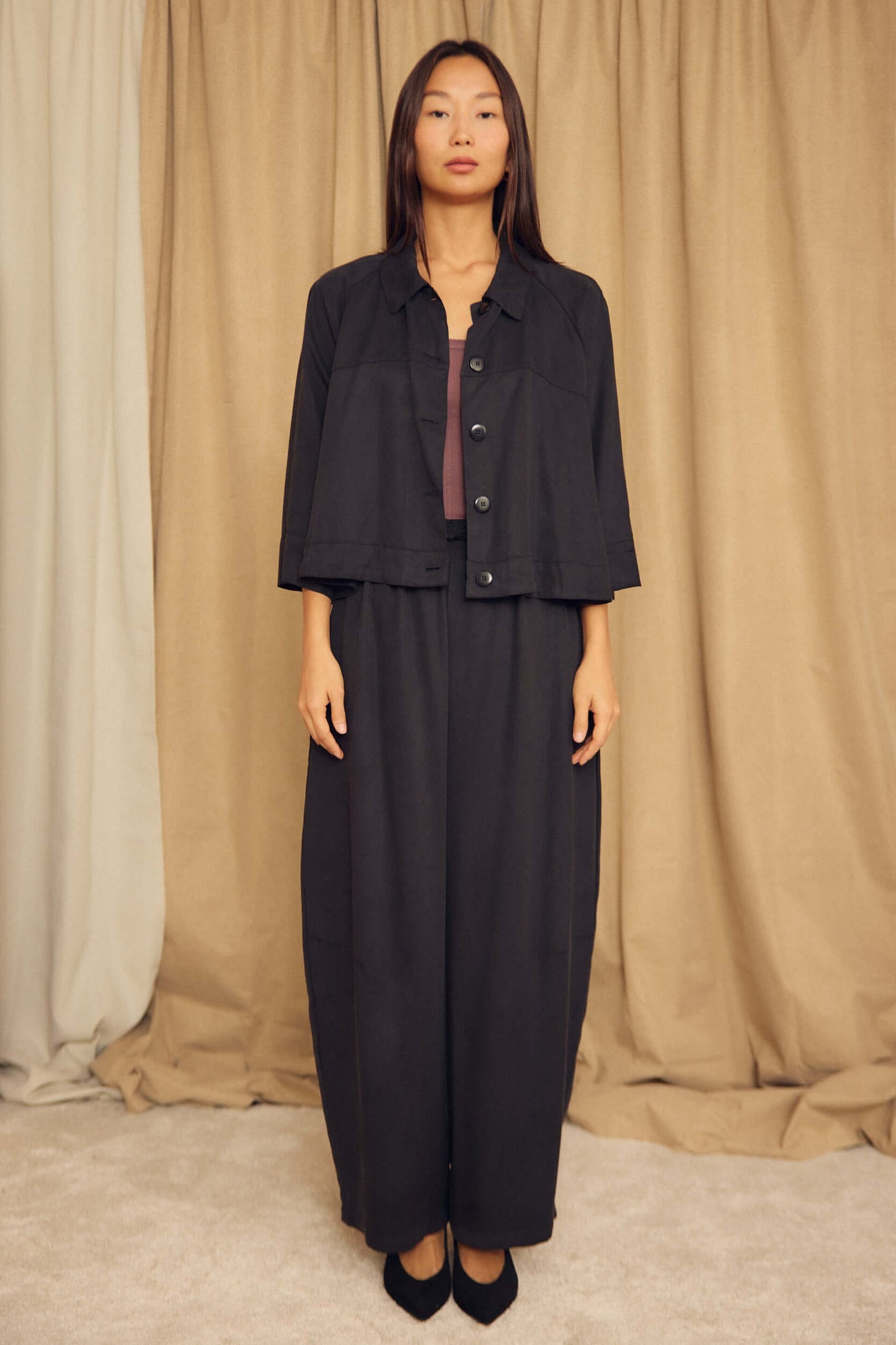 Model wearing the Black Lyocell Flared Jacket styled with a matching ensemble against a neutral backdrop.