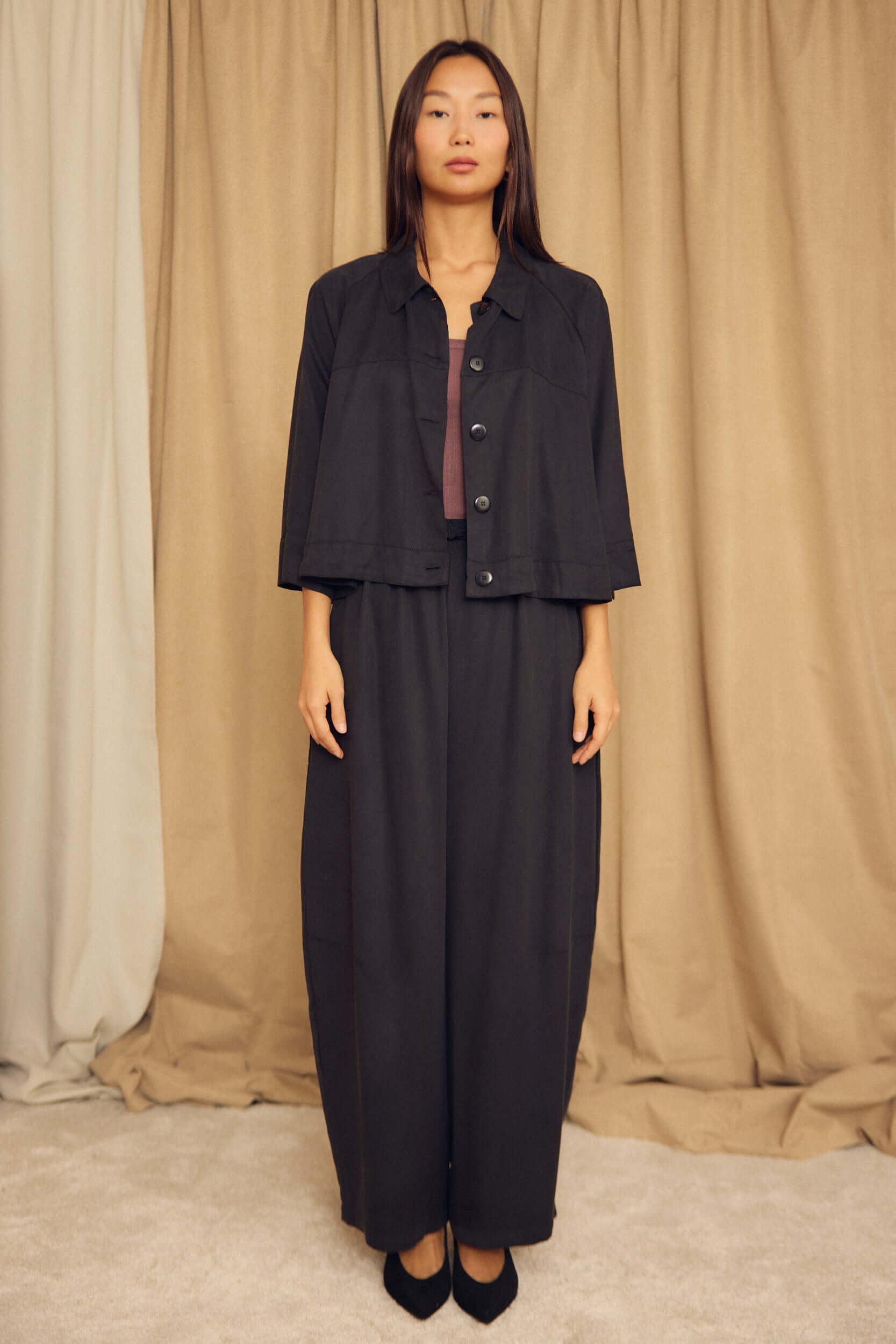 Model wearing the Black Lyocell Flared Jacket styled with a matching ensemble against a neutral backdrop.