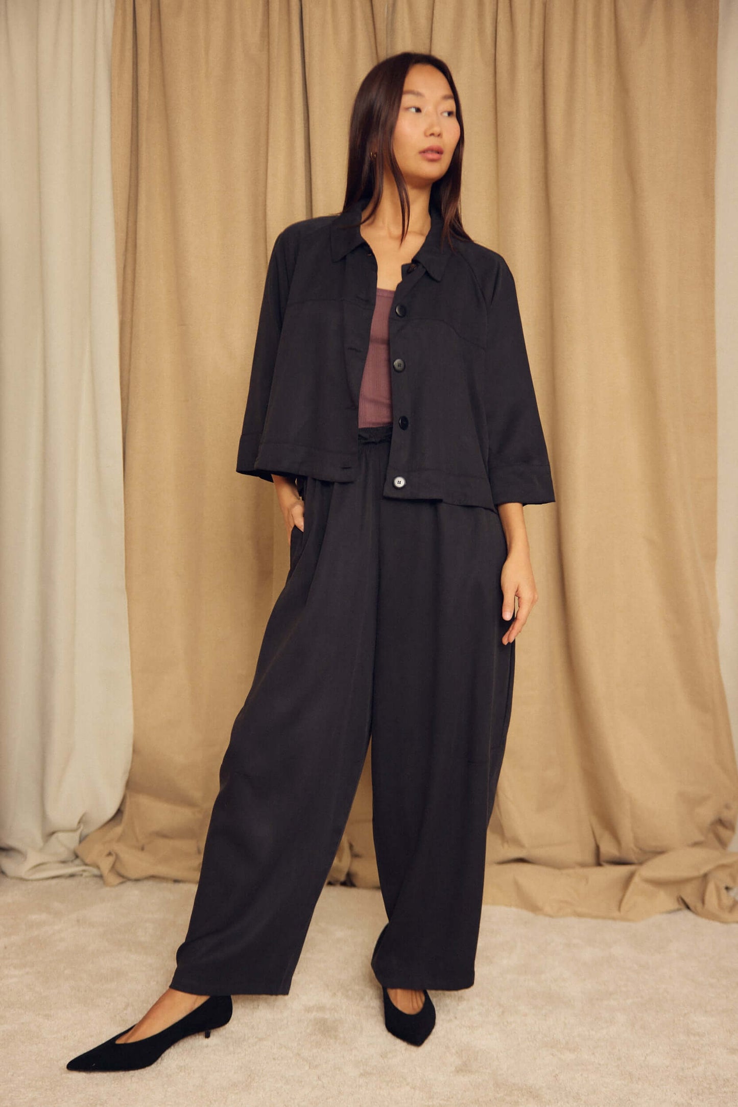 Model wearing a Black Lyocell Flared Jacket with stylish loose pants in a neutral setting.