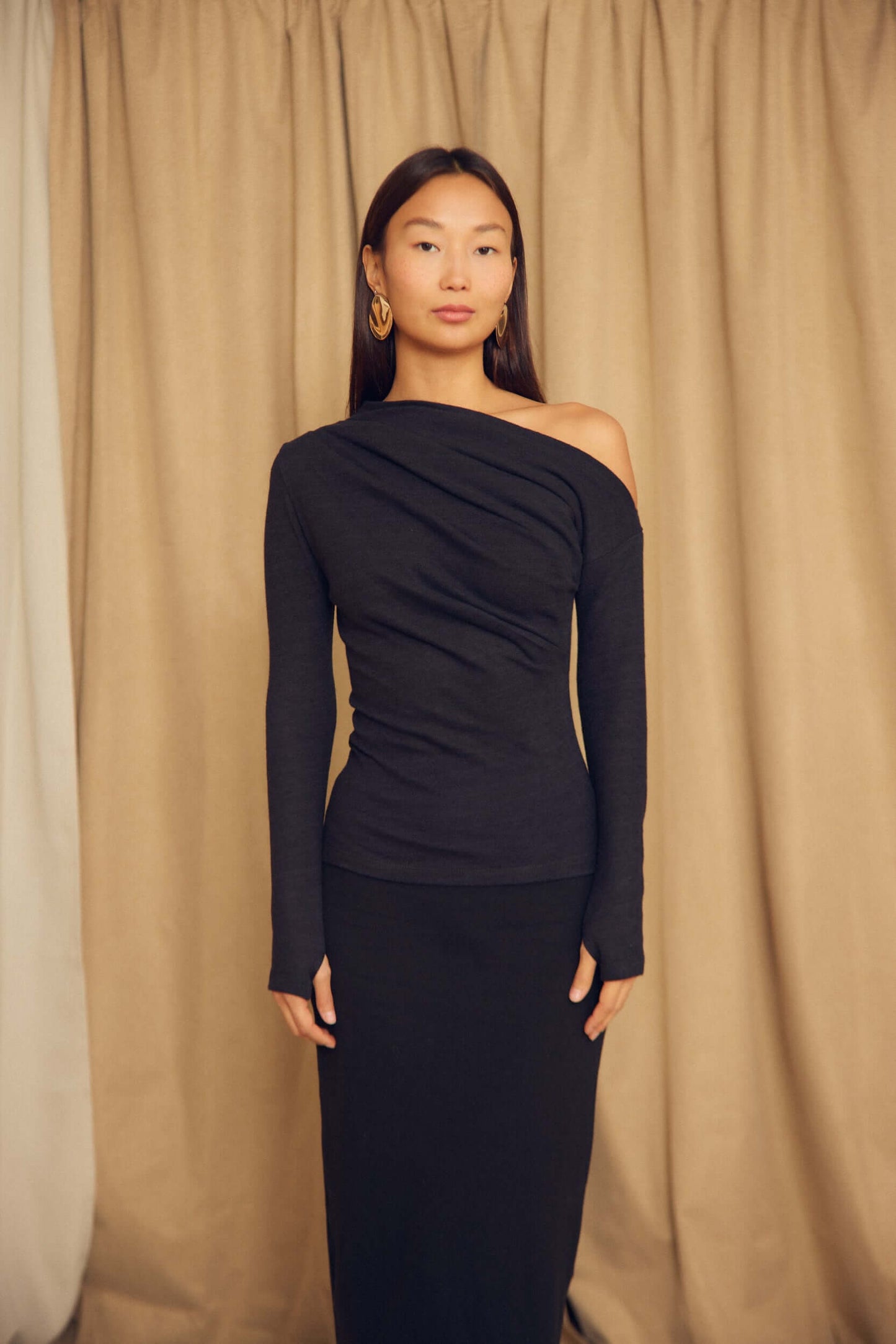 Model wearing a Black Wool Drape Top with thumb holes, featuring an elegant draped neckline and fitted silhouette.