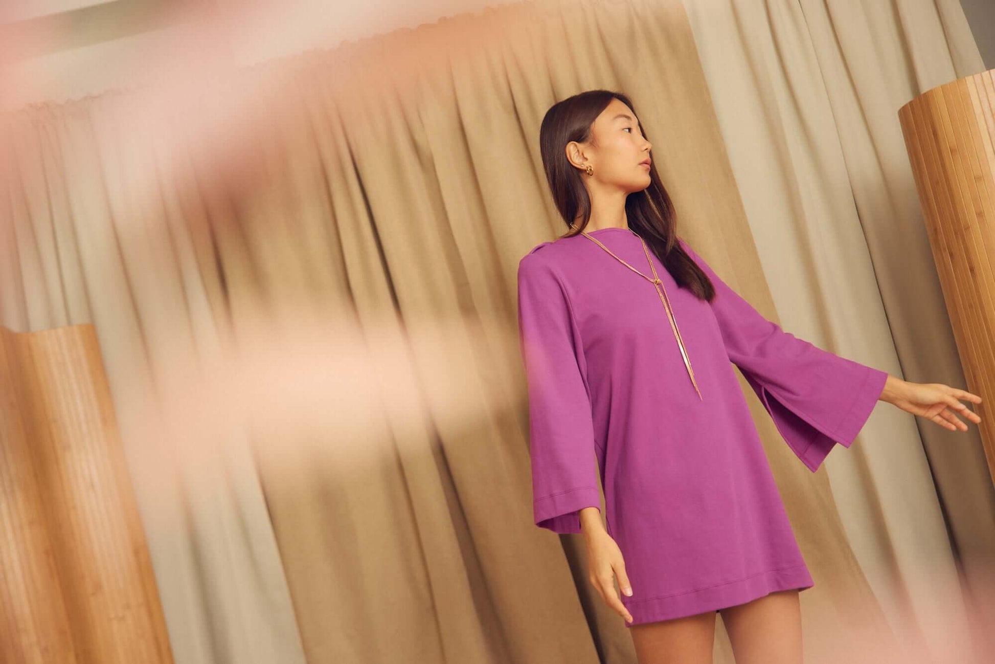 Model wearing Plum Organic Cotton Mini Dress with Flared Sleeves, featuring a vibrant purple color and elegant flared sleeves.
