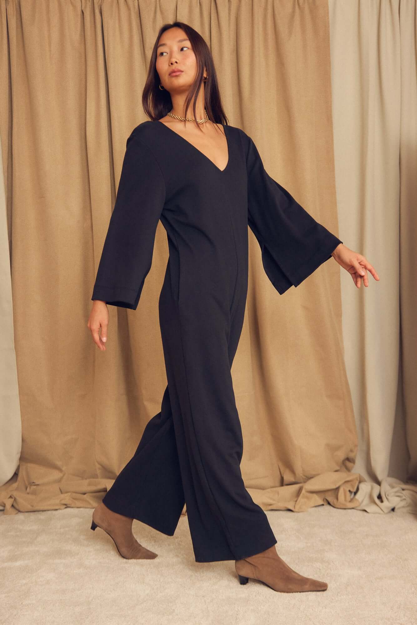 Model wearing a Black Organic Cotton Wide-Leg Jumpsuit with flared sleeves against a neutral backdrop.