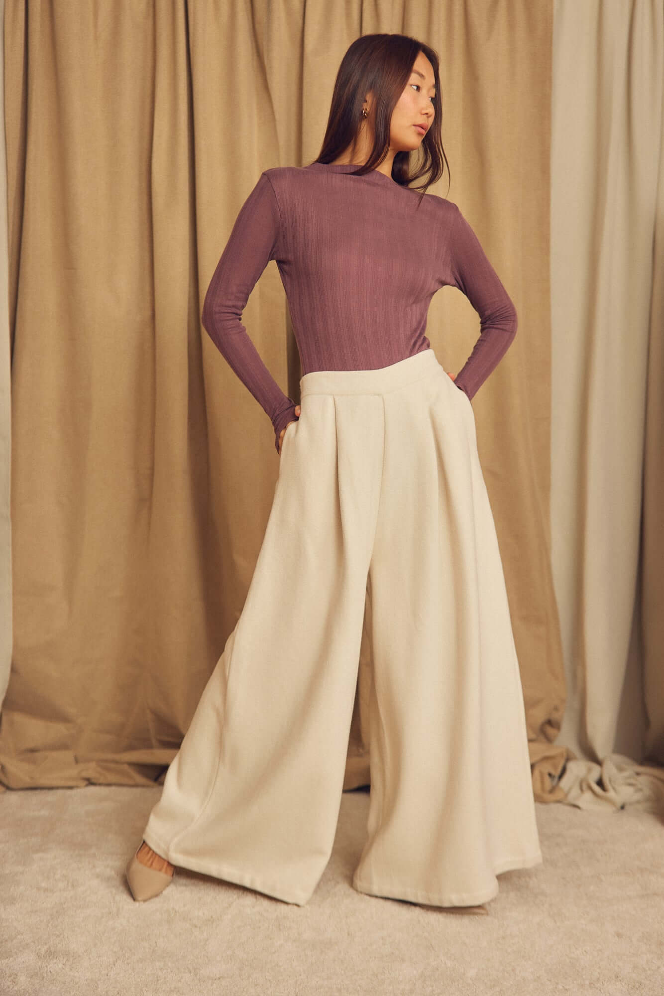 Woman wearing Ecru Organic Cotton Wide Trousers with a fitted long-sleeve top, posing against a neutral backdrop.