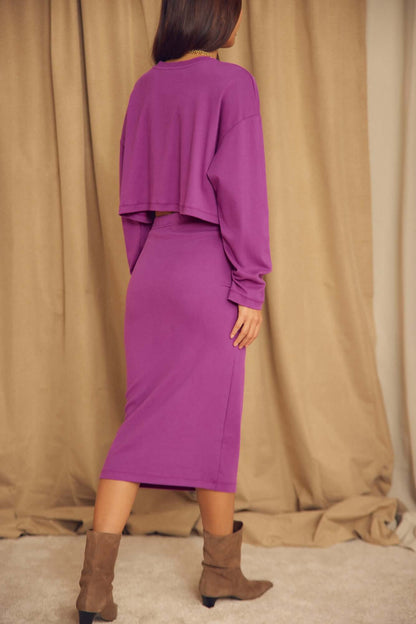 Model wearing Plum Organic Cotton Pencil Midi Skirt paired with a cropped purple top and ankle boots.
