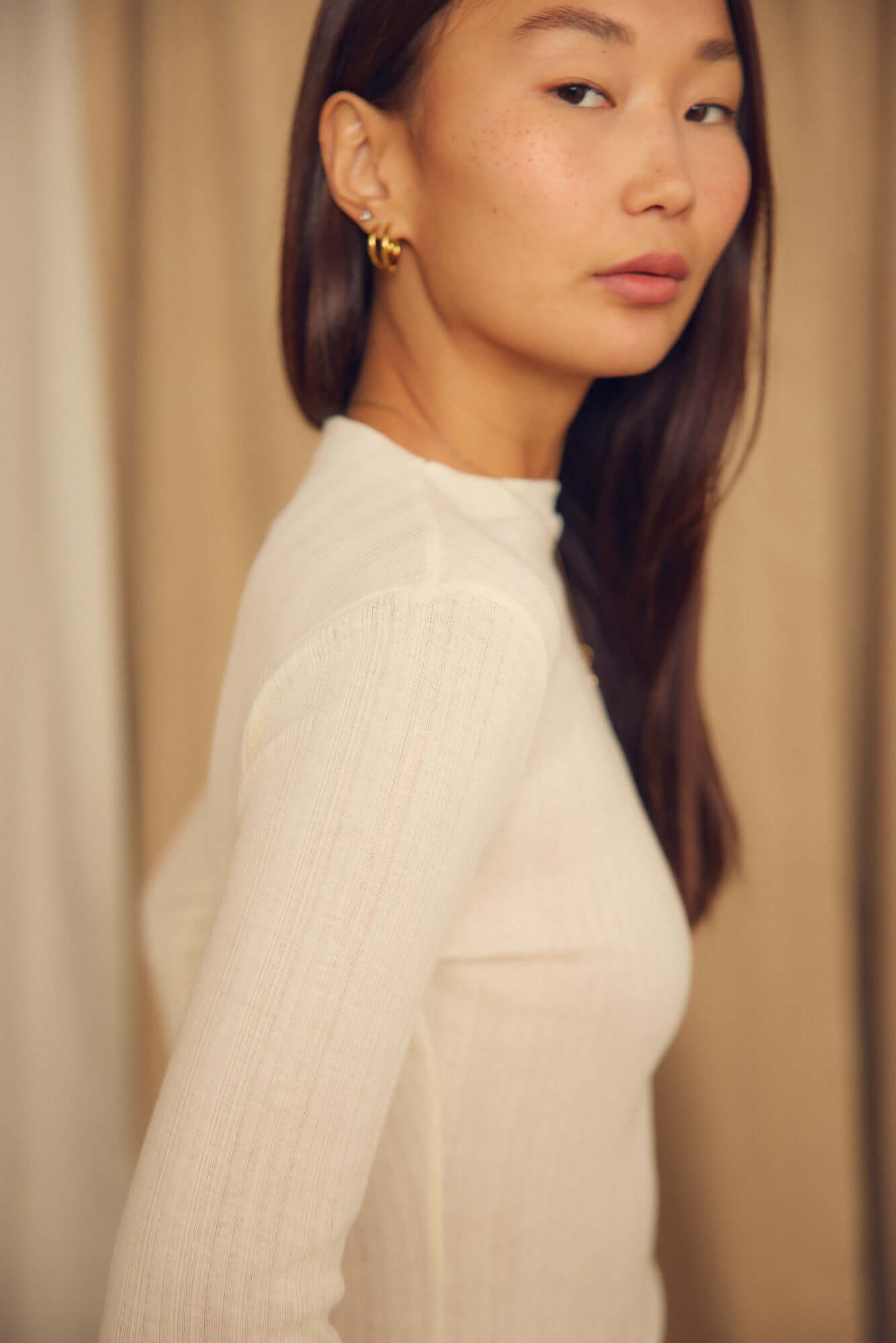 Model wearing Ecru Lyocell Ribbed Long Sleeve Top, highlighting its fine ribbed texture and elegant silhouette.