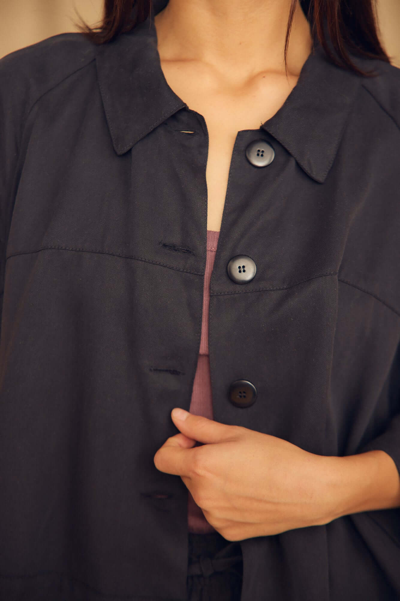Close-up of a person wearing the Black Lyocell Flared Jacket with black buttons and elegant collar.