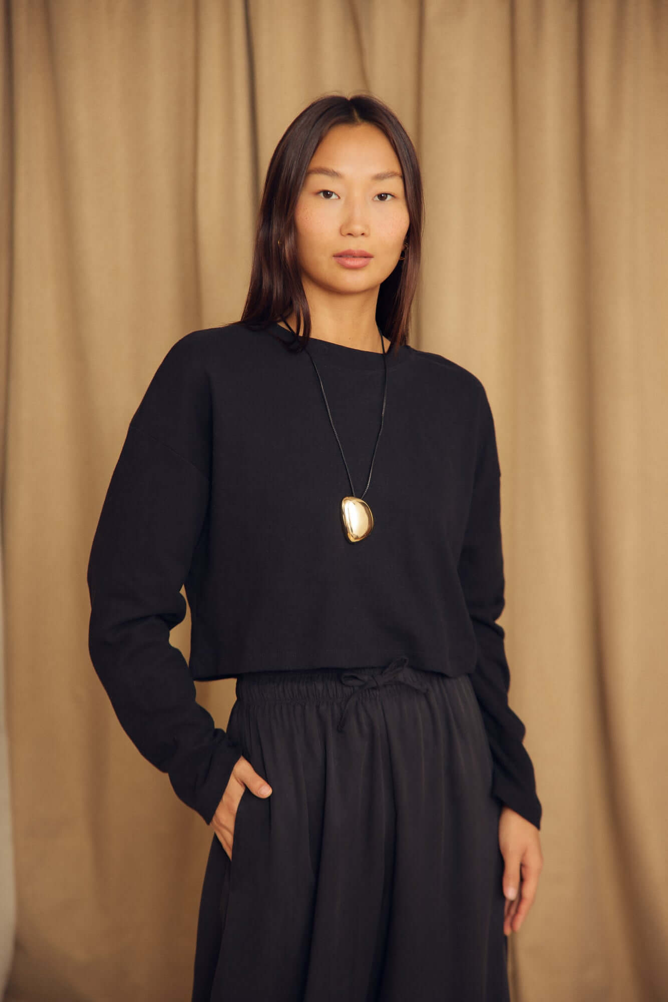 Model wearing a Black Organic Cotton Oversized Crop Top with long sleeves and a relaxed fit.