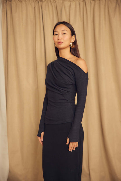 Black Wool Drape Top with Thumb Holes shown on a model, featuring an elegant draped neckline and fitted silhouette.