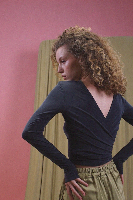 Woman wearing a Cupro Multiway Wrap Top in Slate Black, showcasing its stylish design and flattering fit.