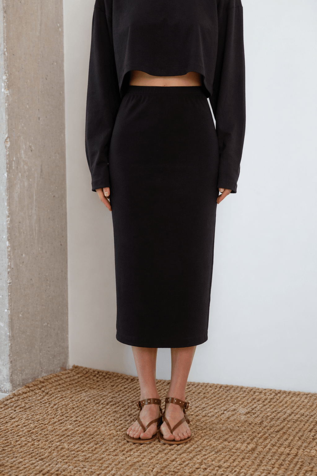 Organic Cotton Midi Skirt in Black worn with a matching black crop top and sandals, perfect for stylish spring-summer looks.