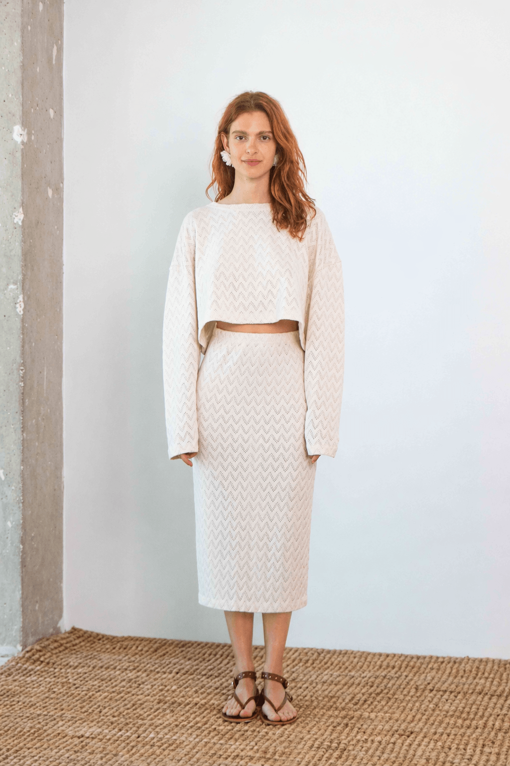 Model wearing a Crochet Organic Cotton Midi Skirt paired with a matching cropped sweater in ecru, showcasing modern elegance.