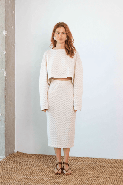 Model wearing a Crochet Organic Cotton Midi Skirt paired with a matching cropped sweater in ecru, showcasing modern elegance.
