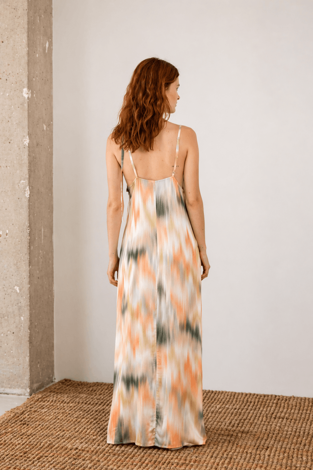 Back view of a woman wearing a Printed Ecovero Viscose Maxi Dress with adjustable straps and a colorful pattern.