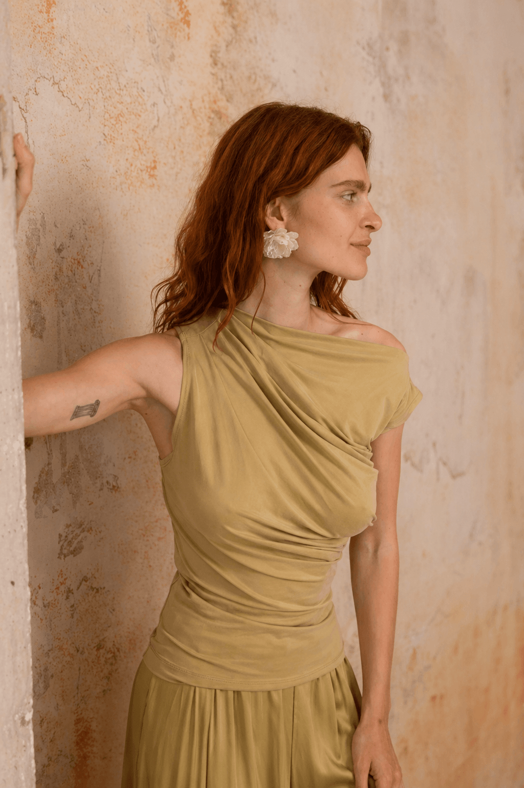 Drape Neckline Cupro Top in Soft Olive showcased on model against a textured wall, exuding elegance and style.
