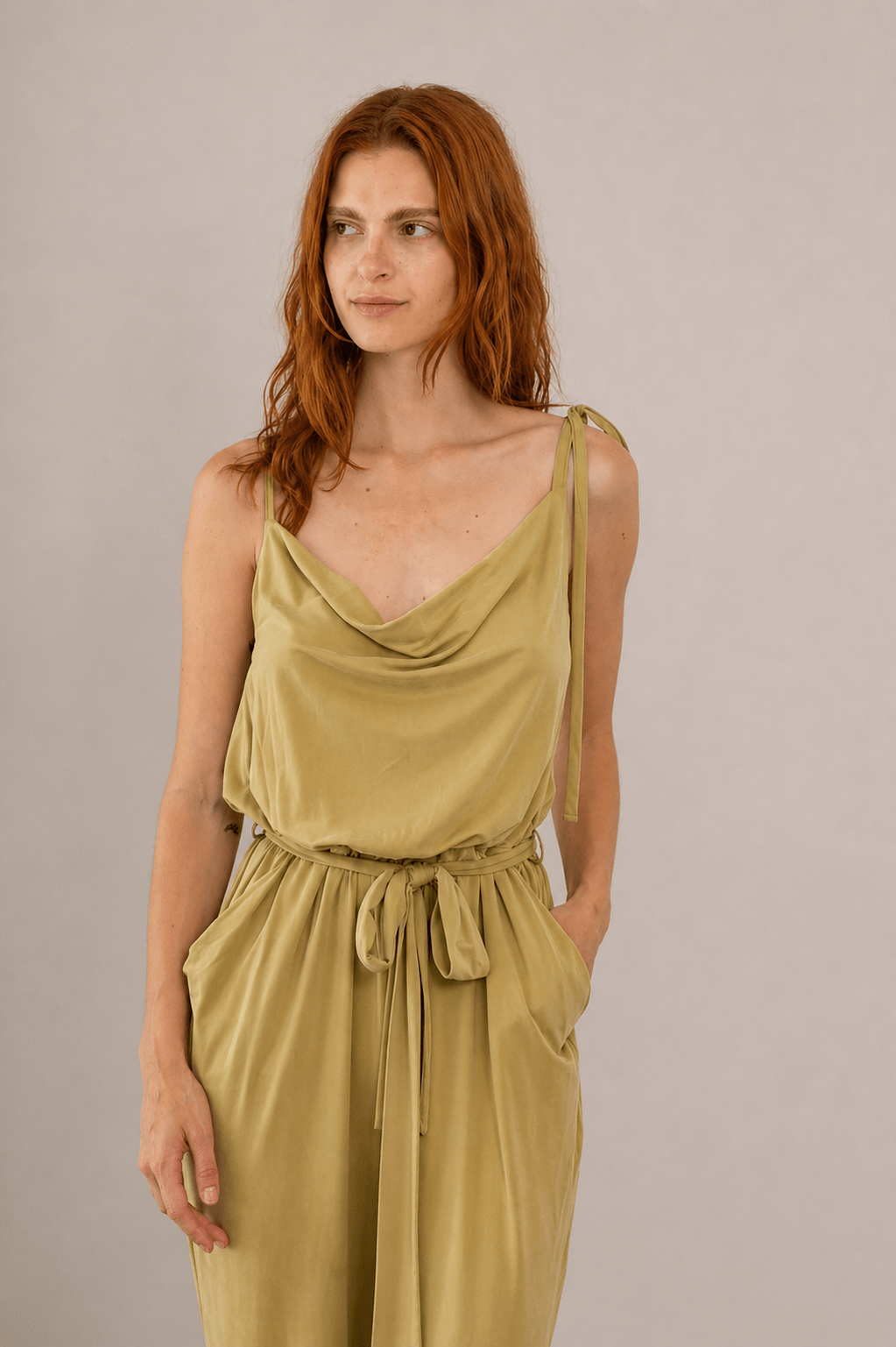 Model wearing Cupro Slip Jumpsuit with Belt in Olive, showcasing its relaxed elegance and soft drape.