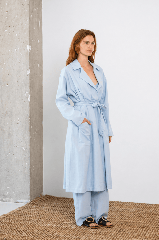 Lightweight Organic Cotton Trench Coat in Pale Blue on a model, showcasing its relaxed silhouette and detachable belt.