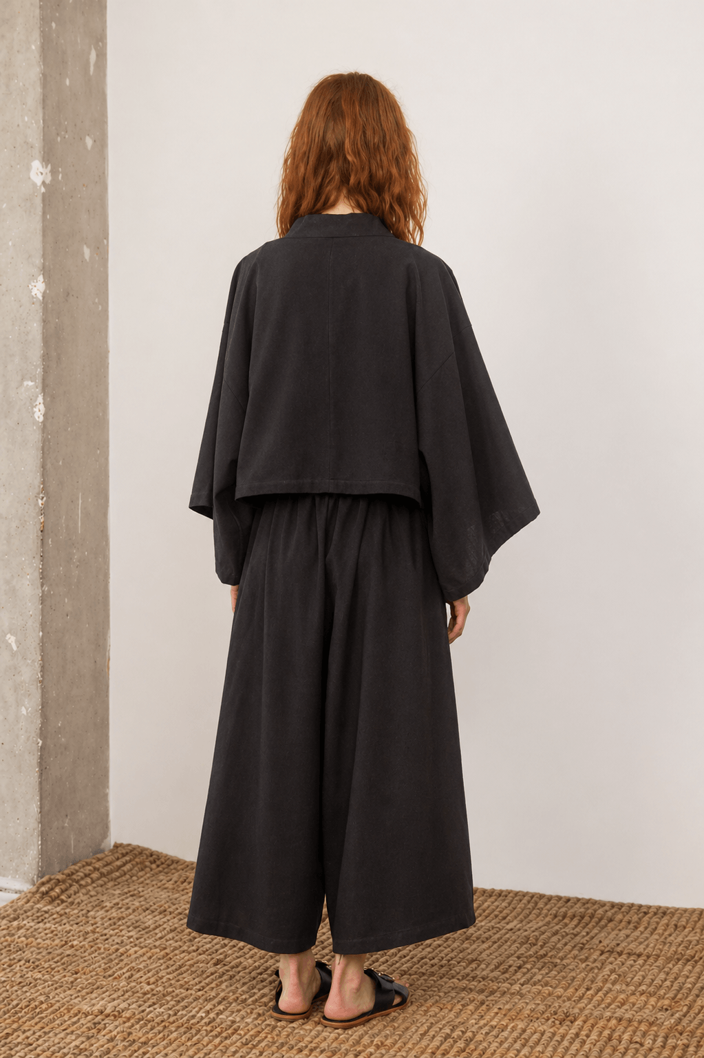Organic Cotton Wide Culottes in Black, showing the back view of a model wearing oversized culottes with a relaxed fit.
