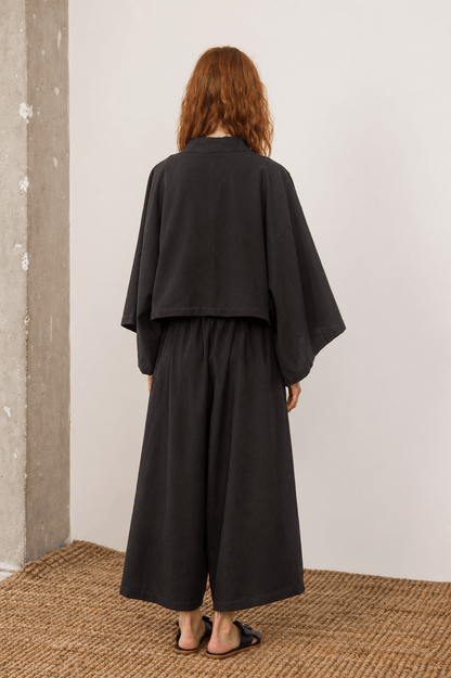 Organic Cotton Wide Culottes in Black, showing the back view of a model wearing oversized culottes with a relaxed fit.