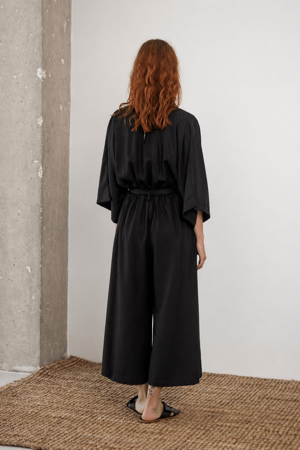 Tencel Kimono Jumpsuit in Black, showcasing a relaxed back view with culotte-style trousers, perfect for warm-weather elegance.