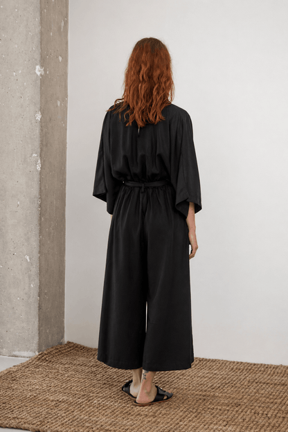 Tencel Kimono Jumpsuit in Black, showcasing a relaxed back view with culotte-style trousers, perfect for warm-weather elegance.