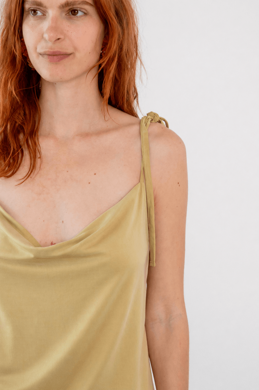 Model wearing Cupro Drape Slip Top in Soft Olive with adjustable straps and a draped neckline.