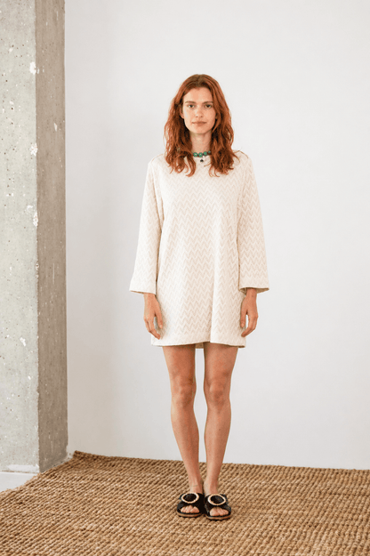 Model wearing an Organic Cotton Crochet Mini Dress in ecru with flared sleeves and a relaxed fit, perfect for warm-weather.