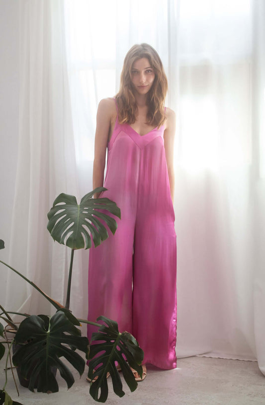 PRINT WIDE JUMPSUIT worn by model with side pockets and adjustable straps, in vibrant pink, set in airy room.
