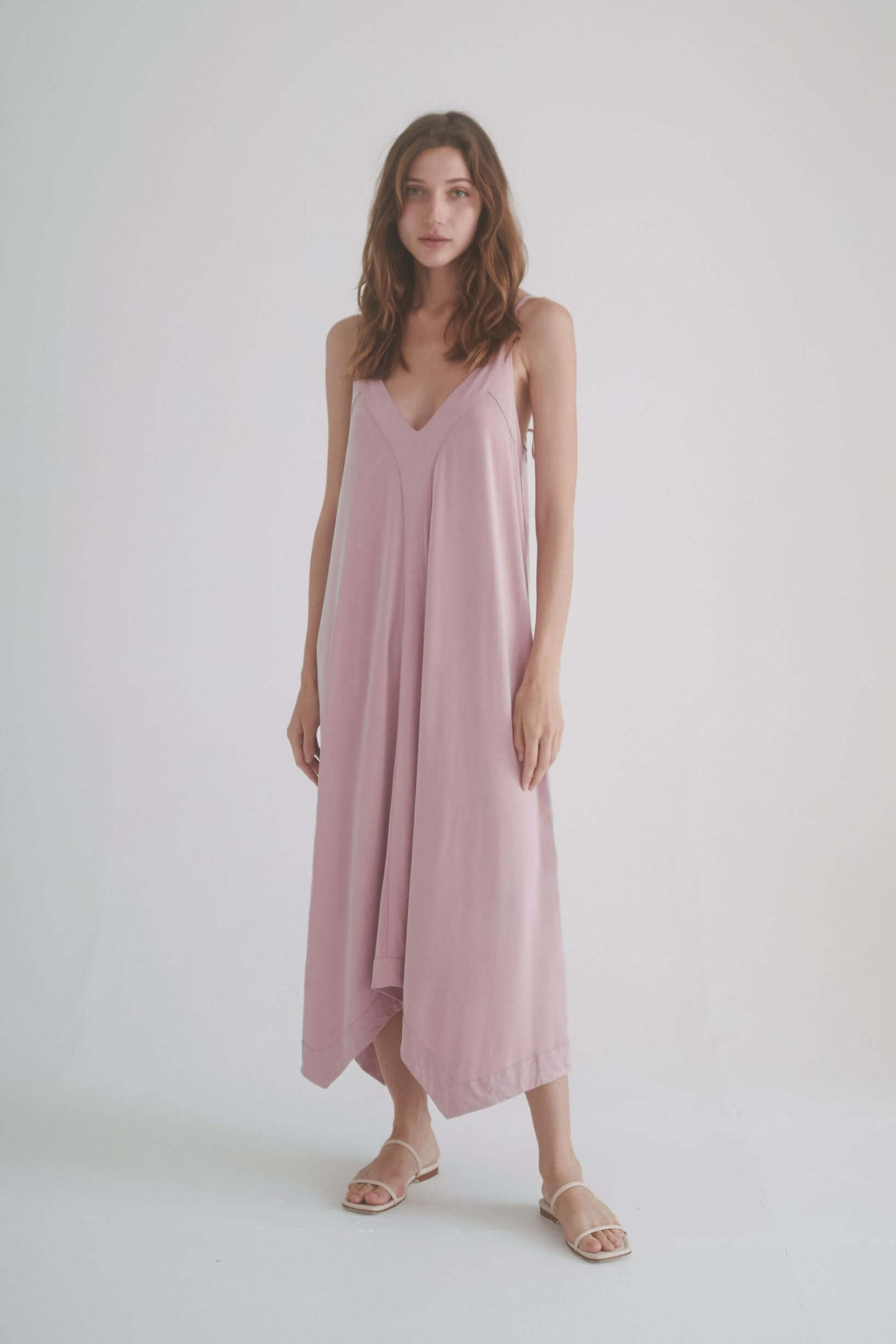 Model wearing a ROSE CUPRO MIDI DRESS in blush, featuring adjustable straps and a flowy design.