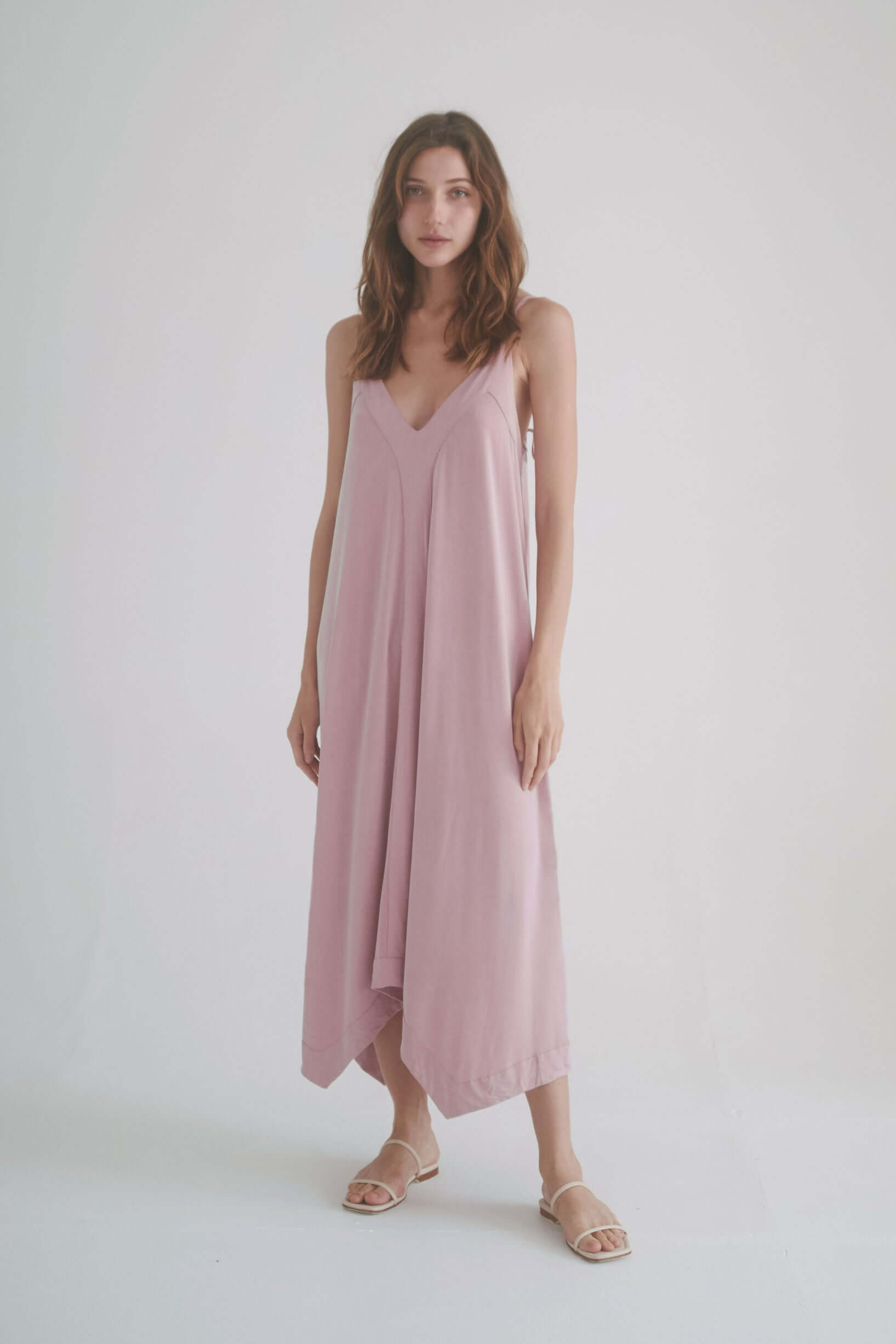 Model wearing a ROSE CUPRO MIDI DRESS in blush, featuring adjustable straps and a flowy design.