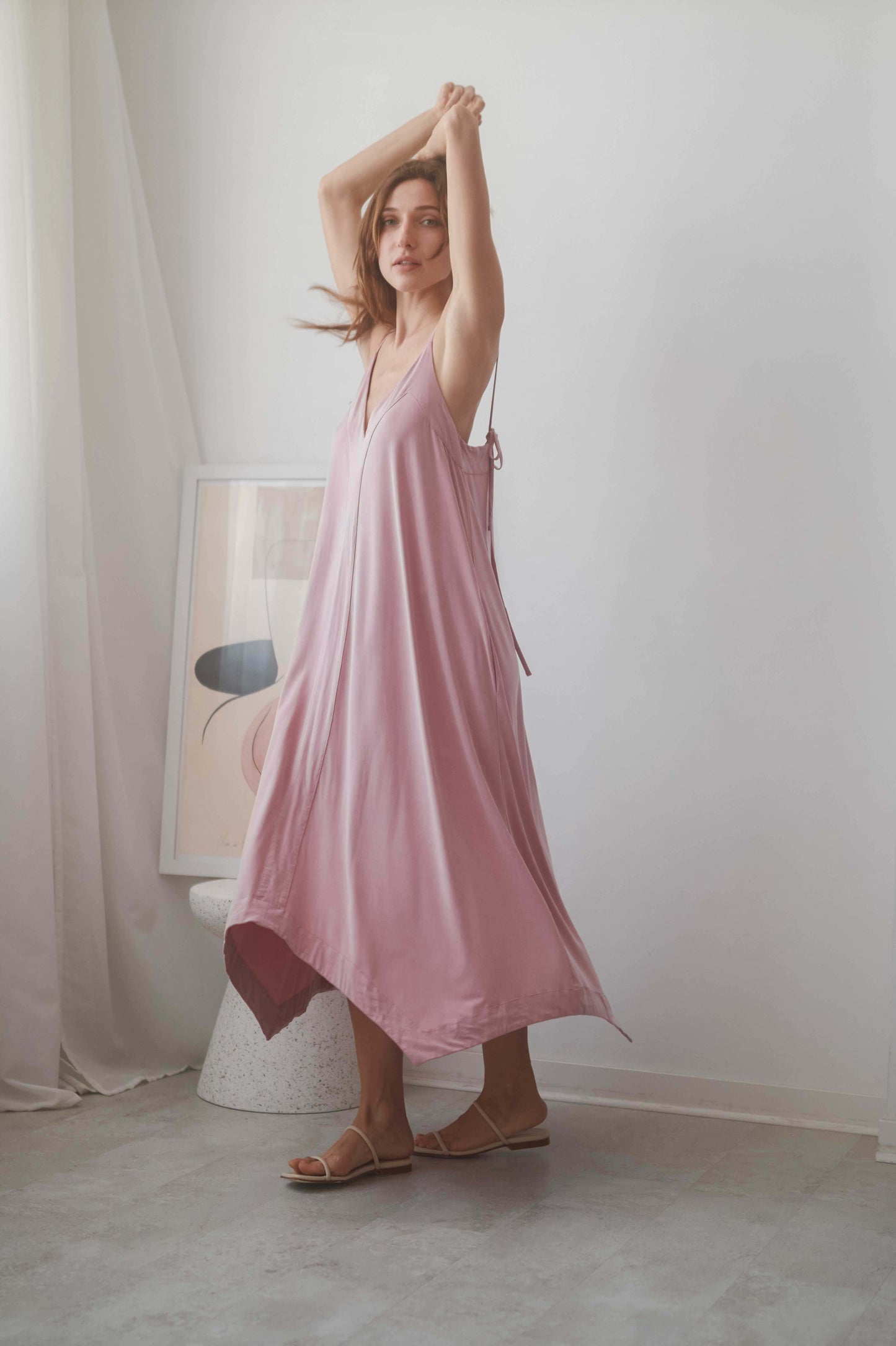 Model wearing a ROSE CUPRO MIDI DRESS in blush, showcasing adjustable self-tie straps and flowy design.