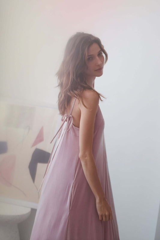 ROSE CUPRO MIDI DRESS worn by a model with self-tie straps in a soft blush color.