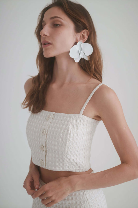 Model wearing ECRU WAFFLE CROP TOP with adjustable straps and floral earrings, showcasing a summer style.