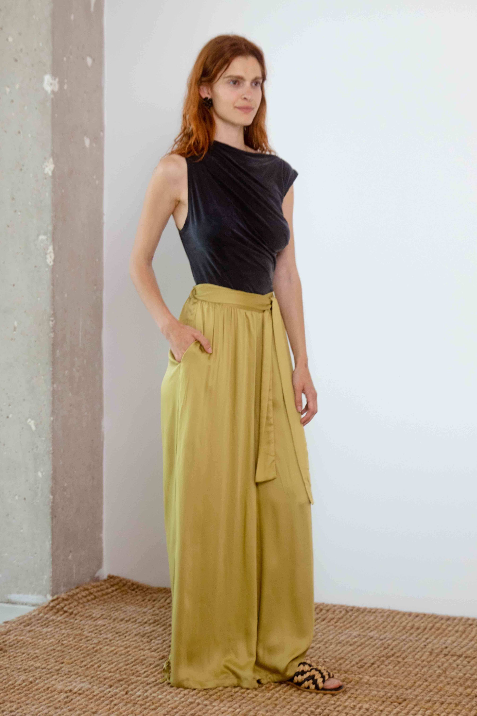 Model wearing Drape Neckline Cupro Top in Black with olive wide-leg trousers.