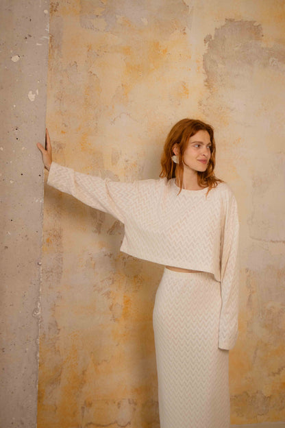 Model wearing a Crochet Organic Cotton Midi Skirt and matching top against a textured wall backdrop.
