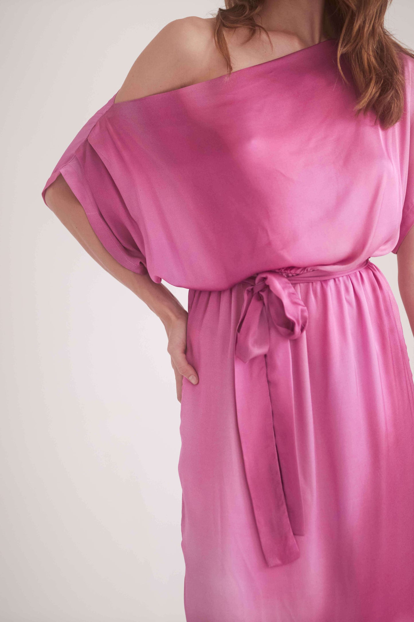 Off-shoulder pink drape dress with a belt, showcasing a stylish and feminine design.