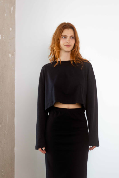 Model wearing Organic Cotton Long Sleeve Top in Black with a cropped silhouette and relaxed fit.