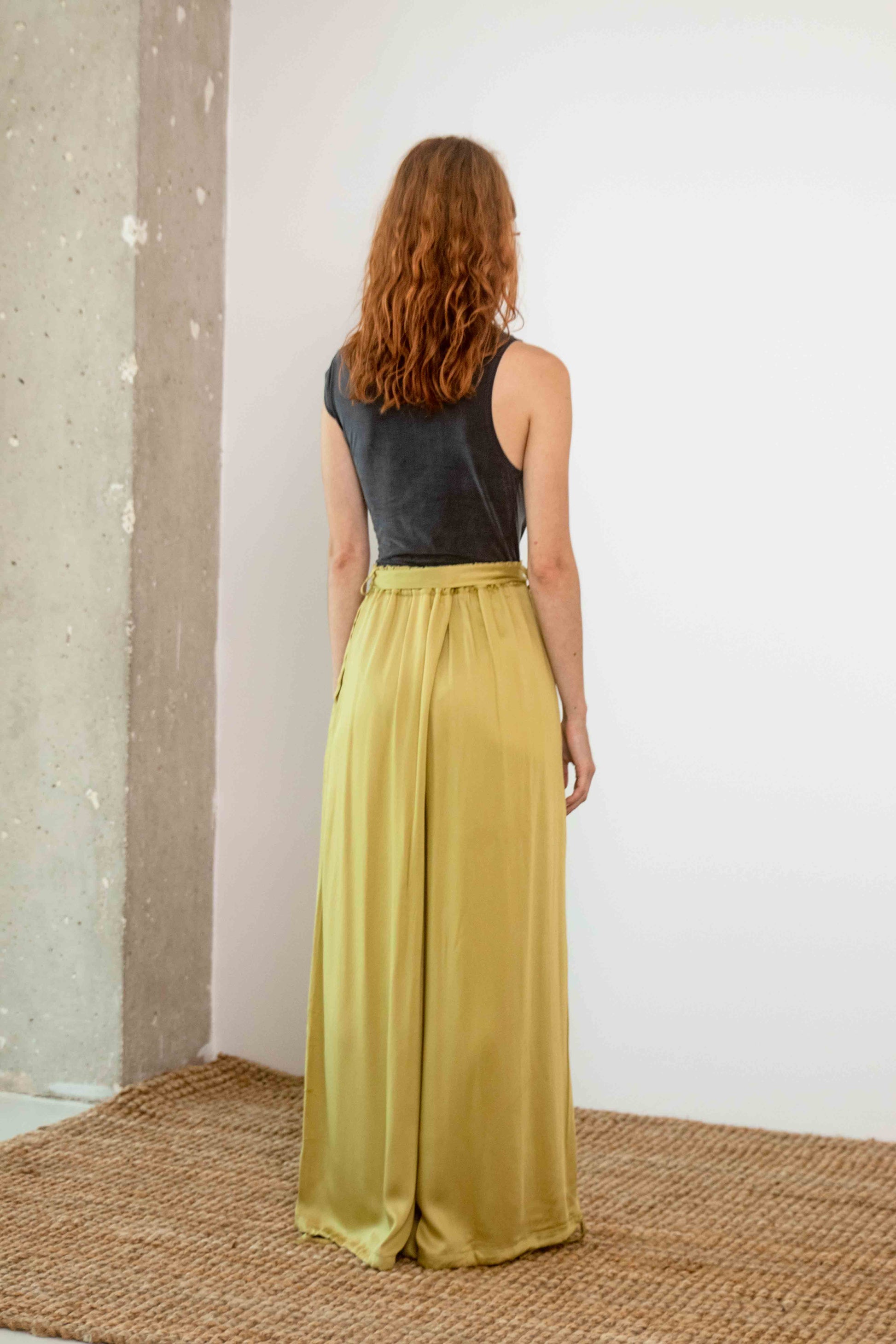 Drape Neckline Cupro Top in Black paired with olive wide-leg pants, showcasing a back view of the outfit.