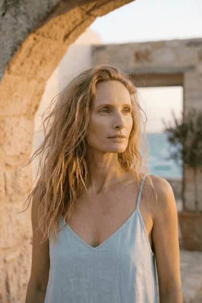 Organic Cotton Wide Jumpsuit in Pale Blue worn by a woman in a sunlit outdoor setting.
