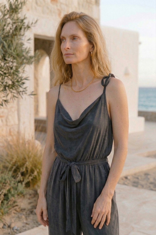 Cupro Slip Jumpsuit with Belt in Slate Black worn outdoors with a natural background.