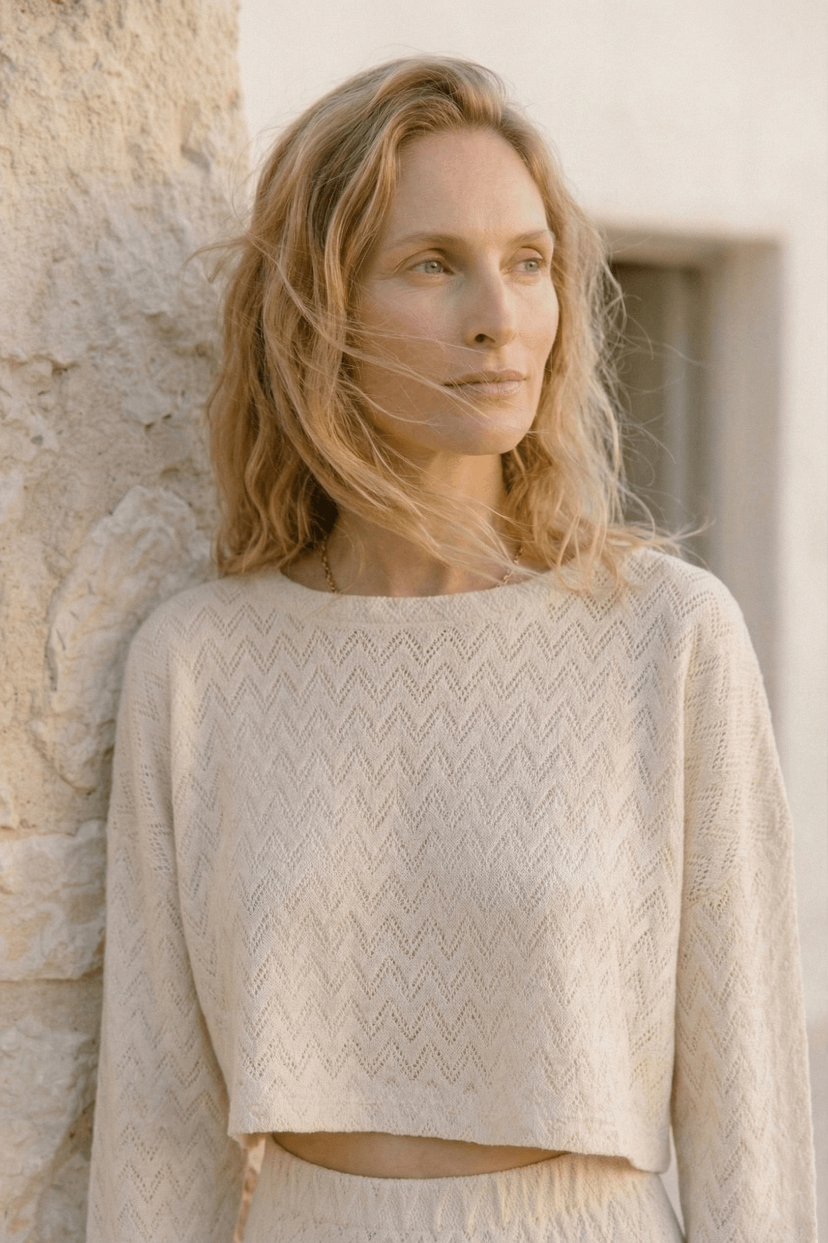 Model wearing a Crochet Organic Cotton Long Sleeve Top in ecru, showcasing its textured crochet design and oversized silhouette.