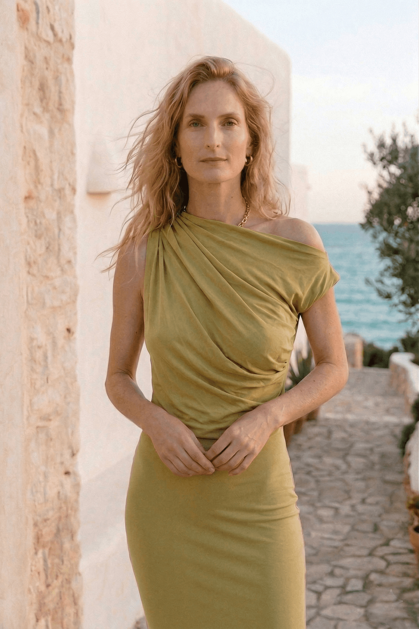 Drape Cupro Midi Dress in Olive worn by a model outdoors, showcasing its elegant draped design and soft olive color.