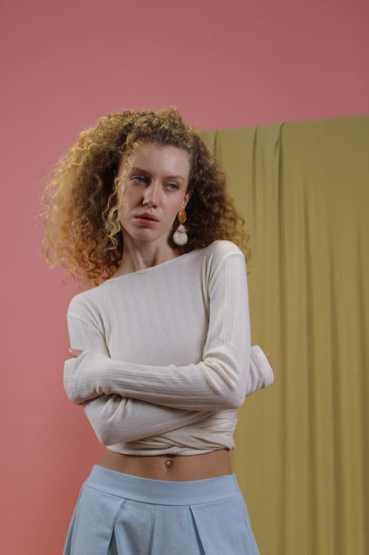 Model wearing Banana Pineapple Multiway Wrap Top in Ecru with stylish earrings and a pastel skirt.