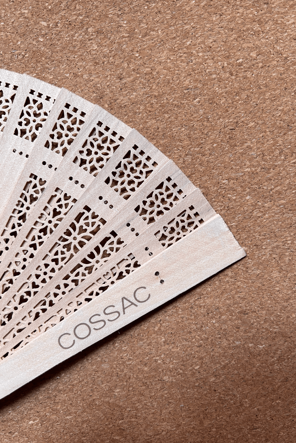 Wooden fan made from recycled wood, featuring intricate design and 'COSSAC' logo, size 30x30cm.