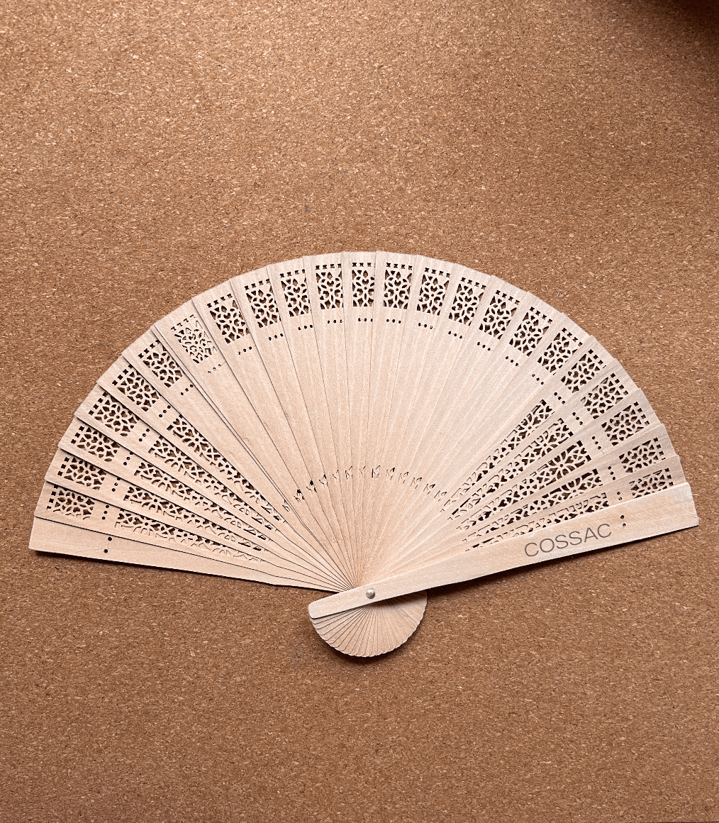 Wooden fan made from recycled wood, 30x30cm, featuring intricate cutouts and 'COSSAC' logo.