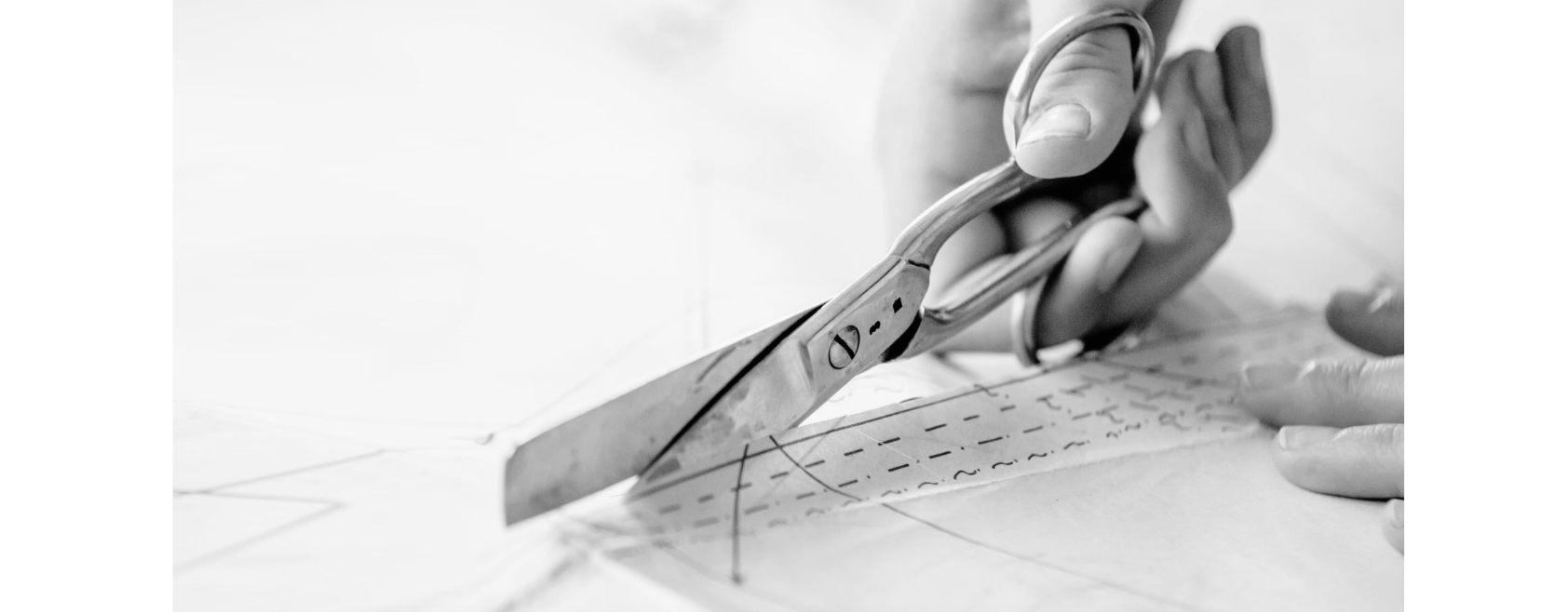 Close-up of hand cutting fabric with scissors on a pattern for fashion design